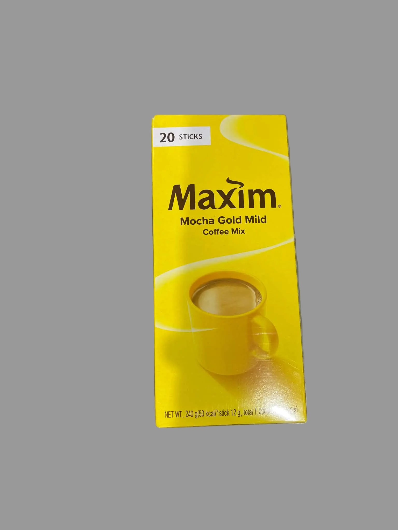 A box of Maxim Mocha Gold Mild Coffee Mix, 20 sticks, featuring a bright yellow packaging with a coffee cup graphic, placed on a gray surface.