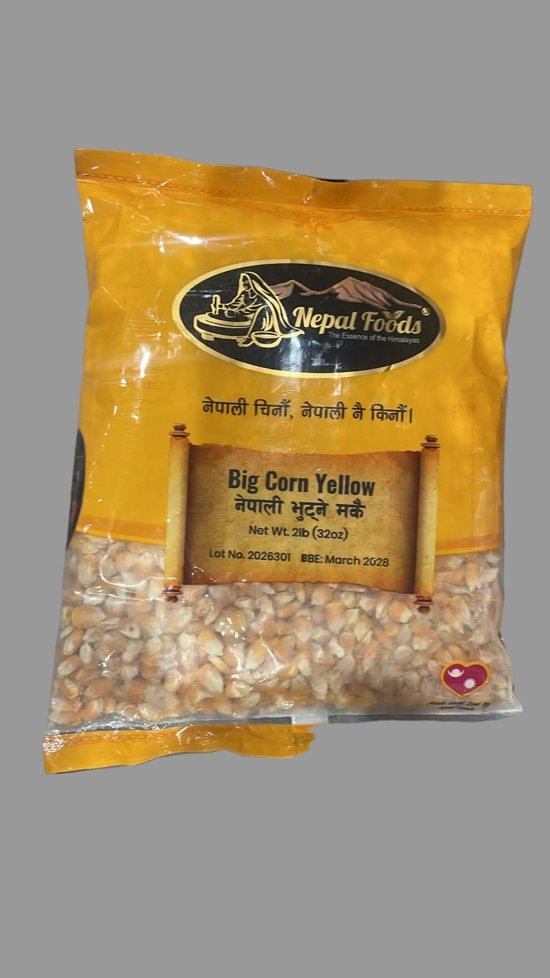 A bag of Nepal Foods Big Corn Yellow (dehydrated corn kernels) in a bright yellow packaging, placed on a gray surface.