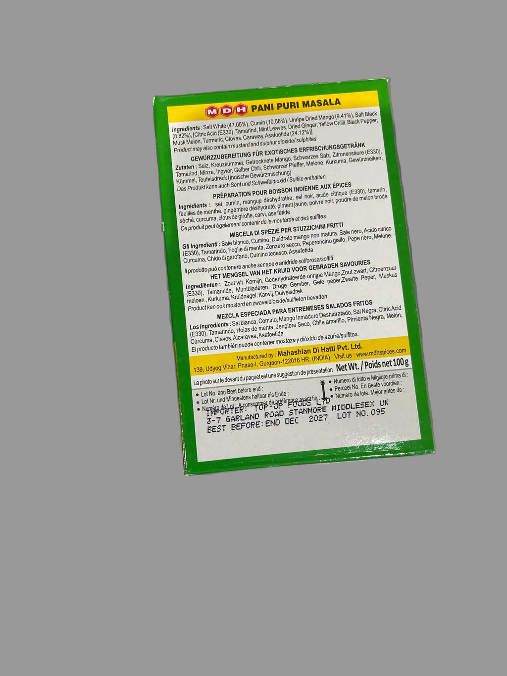 The back of a green and yellow box of Pani Puri Masala food product, photographed on a metallic silver surface.