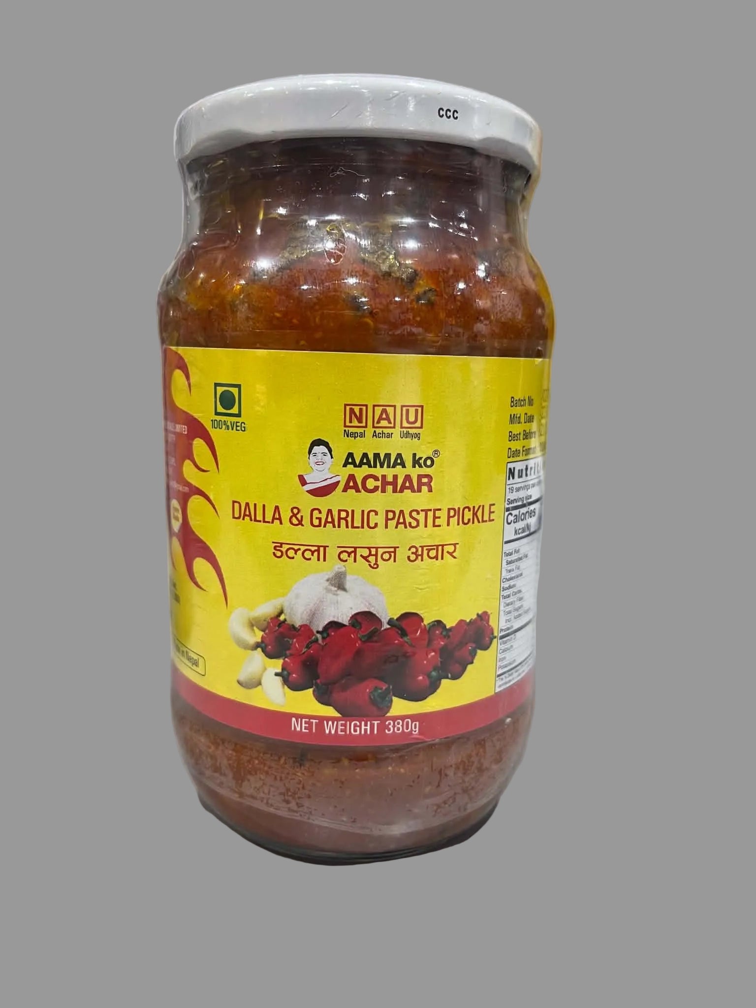 A jar of Aama ko Achar Dalla & Garlic Paste Pickle on a white countertop with a tiled wall in the background.