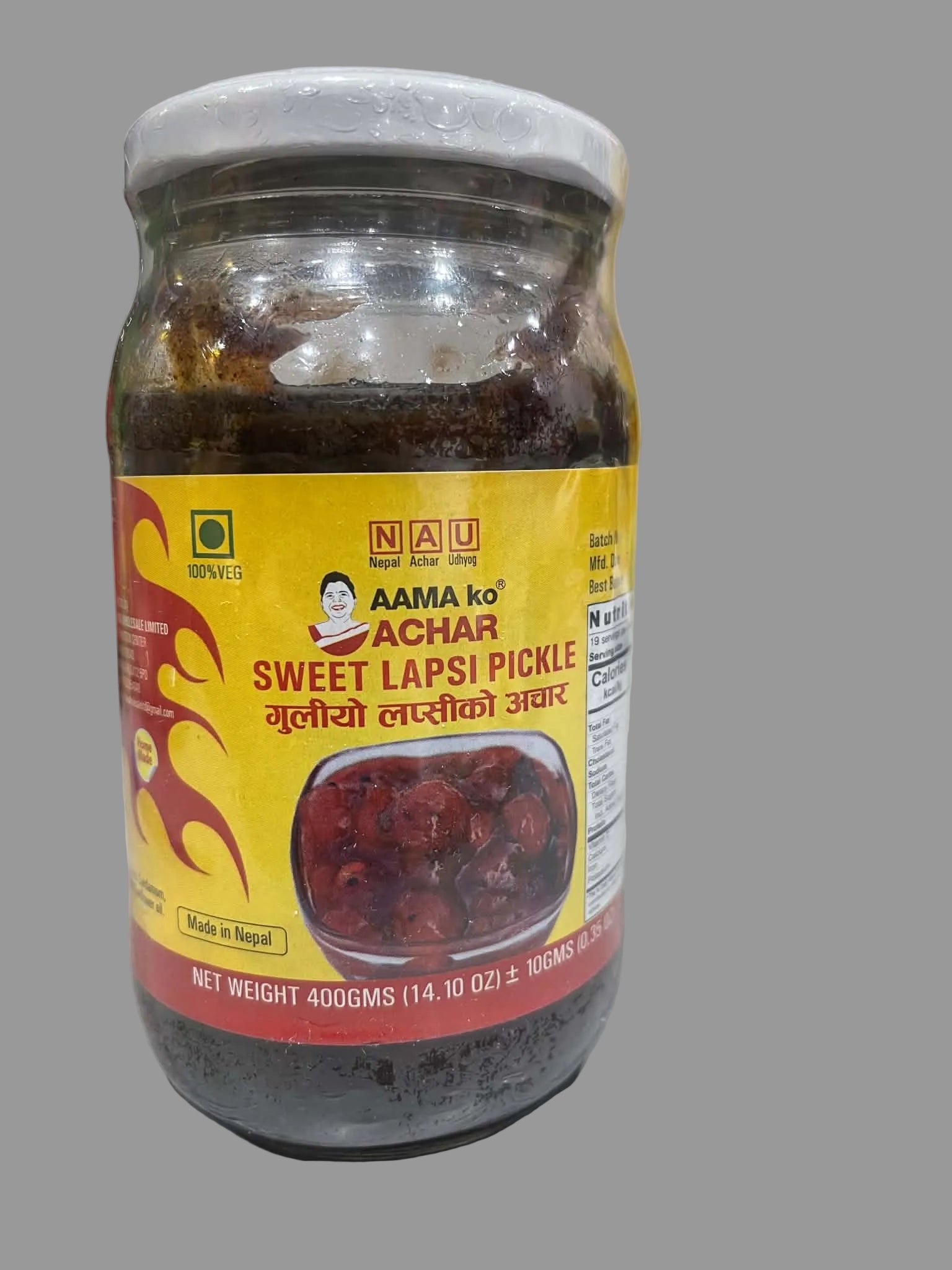 A jar of Nau Achar Sweet Lapsi Pickle on a light-colored countertop with a blurred kitchen background.