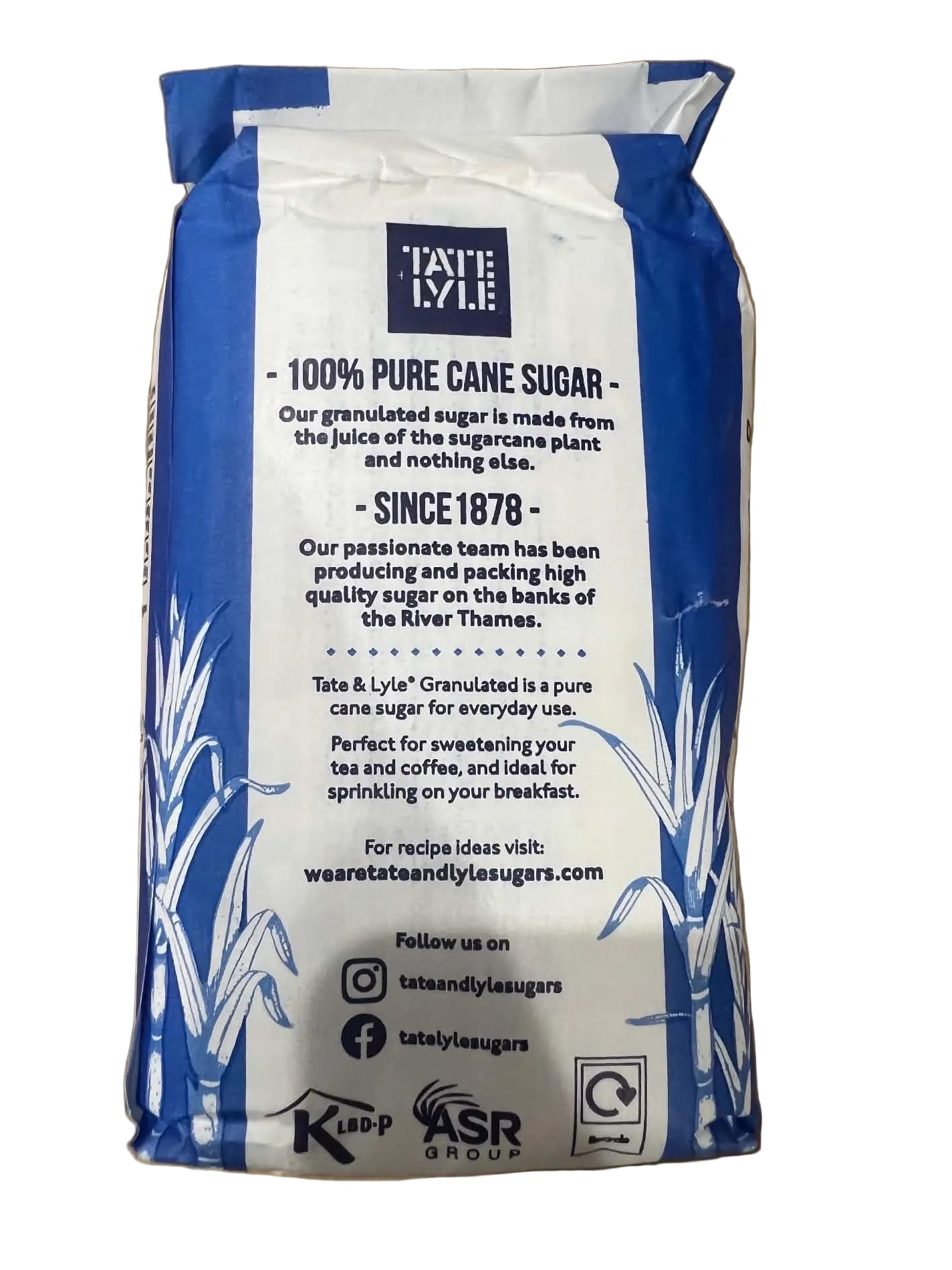 A bag of Kip & Tilt Pure Cane Sugar, 100% pure, shown on a brown cardboard background. The packaging is white with blue graphics and text.