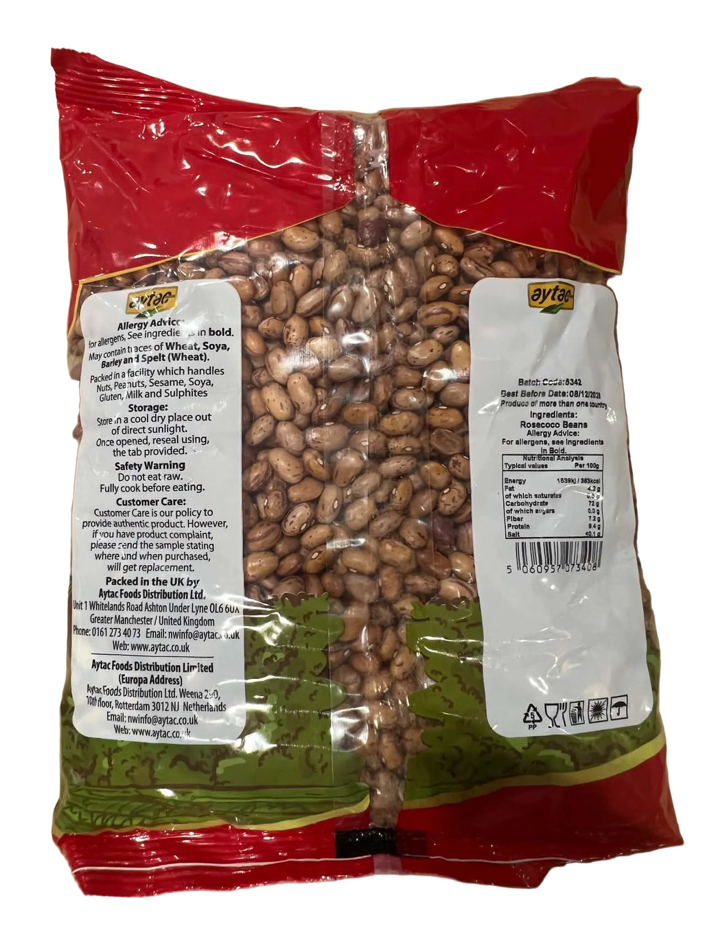 A bag of Spanish olives in a clear plastic package with red and green packaging, showing the brown olives inside, placed on a cardboard surface.