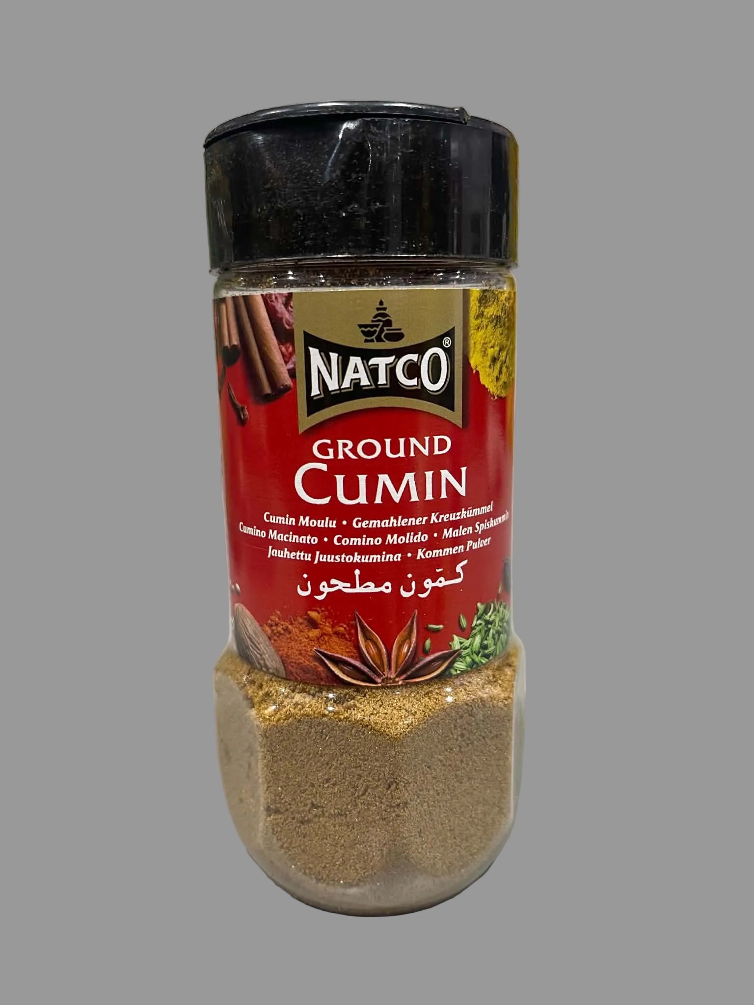 A bottle of Natco Ground Cumin spice powder, showing the brown cumin powder inside a clear jar with a red and black label, set on a light gray surface.