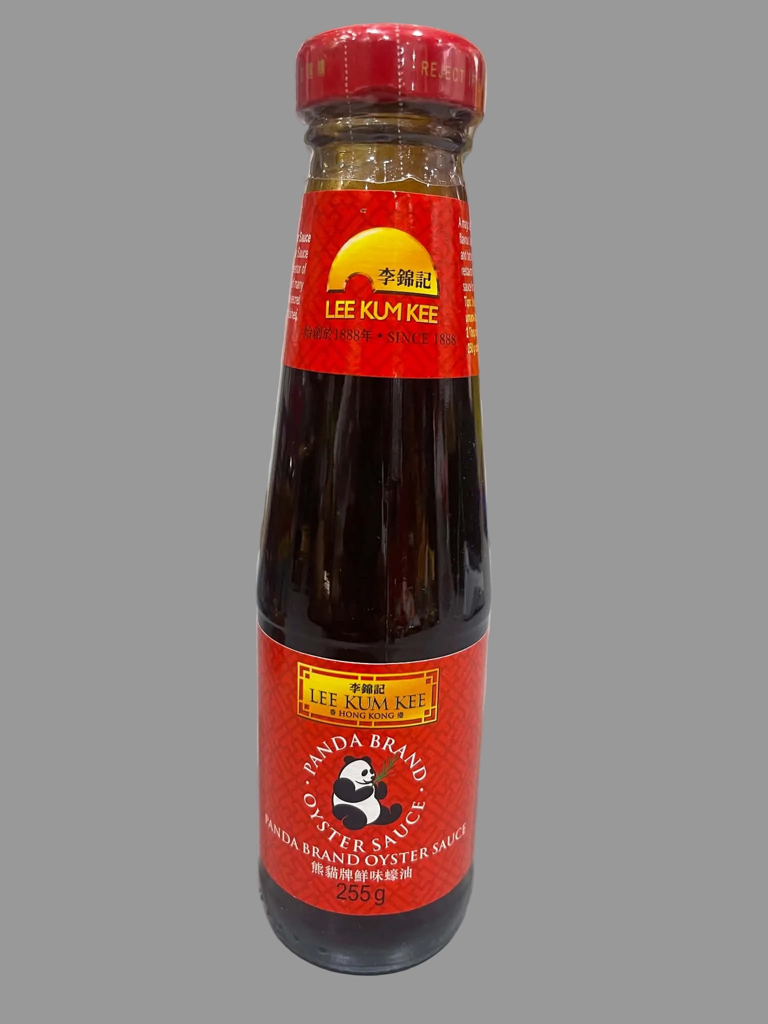 A bottle of Lee Kum Kee Panda Brand Oyster Sauce standing on a light gray surface with a marble-patterned wall in the background.