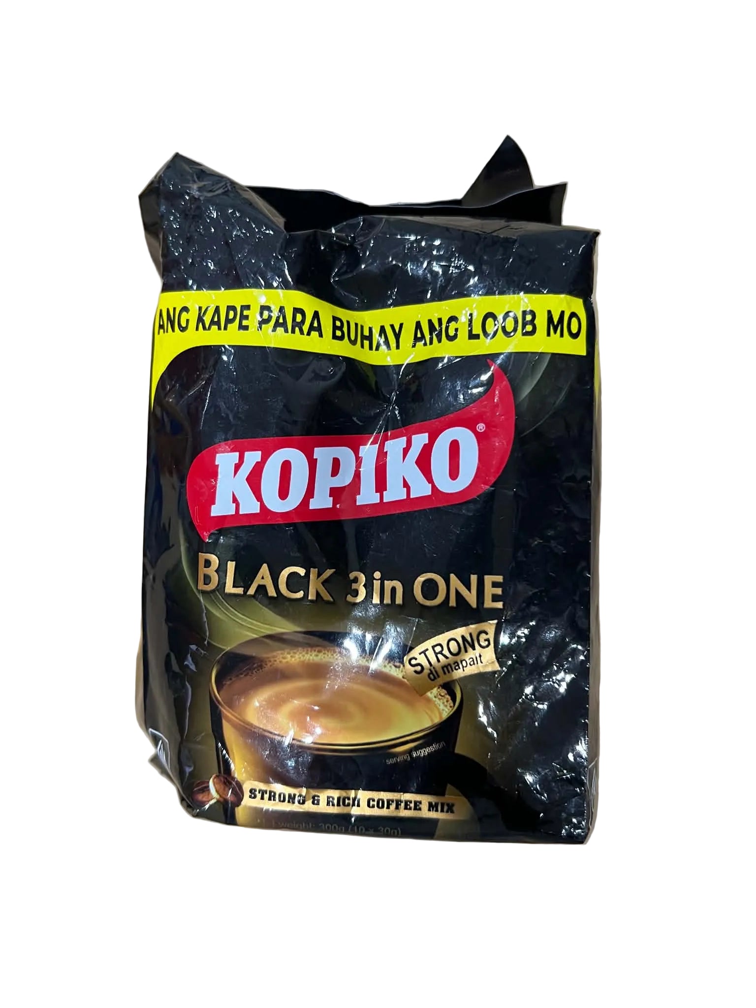 A bag of Kopiko Black 3in1 coffee mix on a light brown cardboard background. The packaging is black with a red and white Kopiko logo, a yellow banner, and a graphic of a cup of coffee.