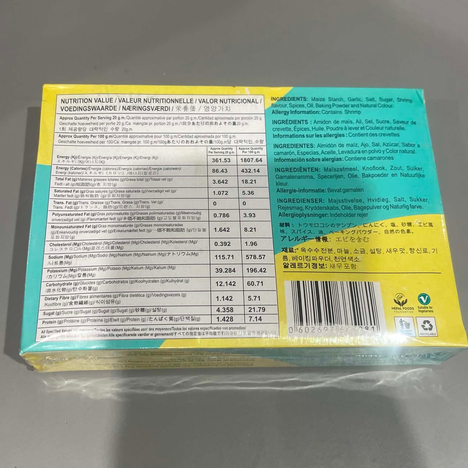 The back of a packaged food box, showing nutrition facts, ingredients, and a barcode, wrapped in clear plastic on a gray surface.