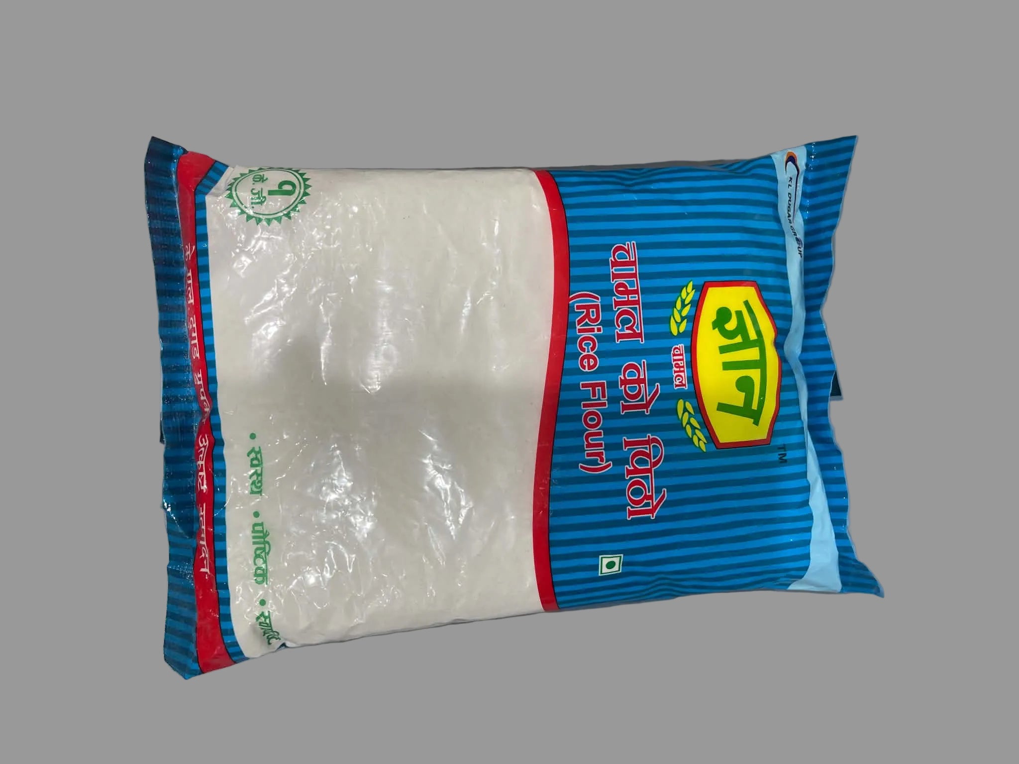 A bag of Kala Dal Dal (rice flour) in blue and white packaging, photographed on a gray surface.