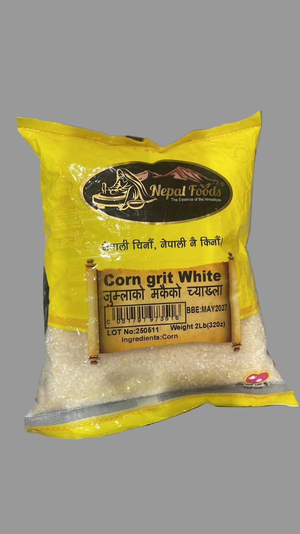 A bag of Nepal Foods Corn Grit White, featuring a bright yellow packaging with a clear lower section showing the white corn grit inside, placed on a gray surface.