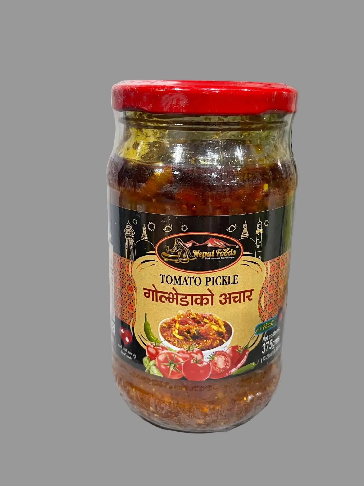A glass jar of Nepal Toldi Tomato Pickle with a red lid and a black and gold label, set on a light gray surface.