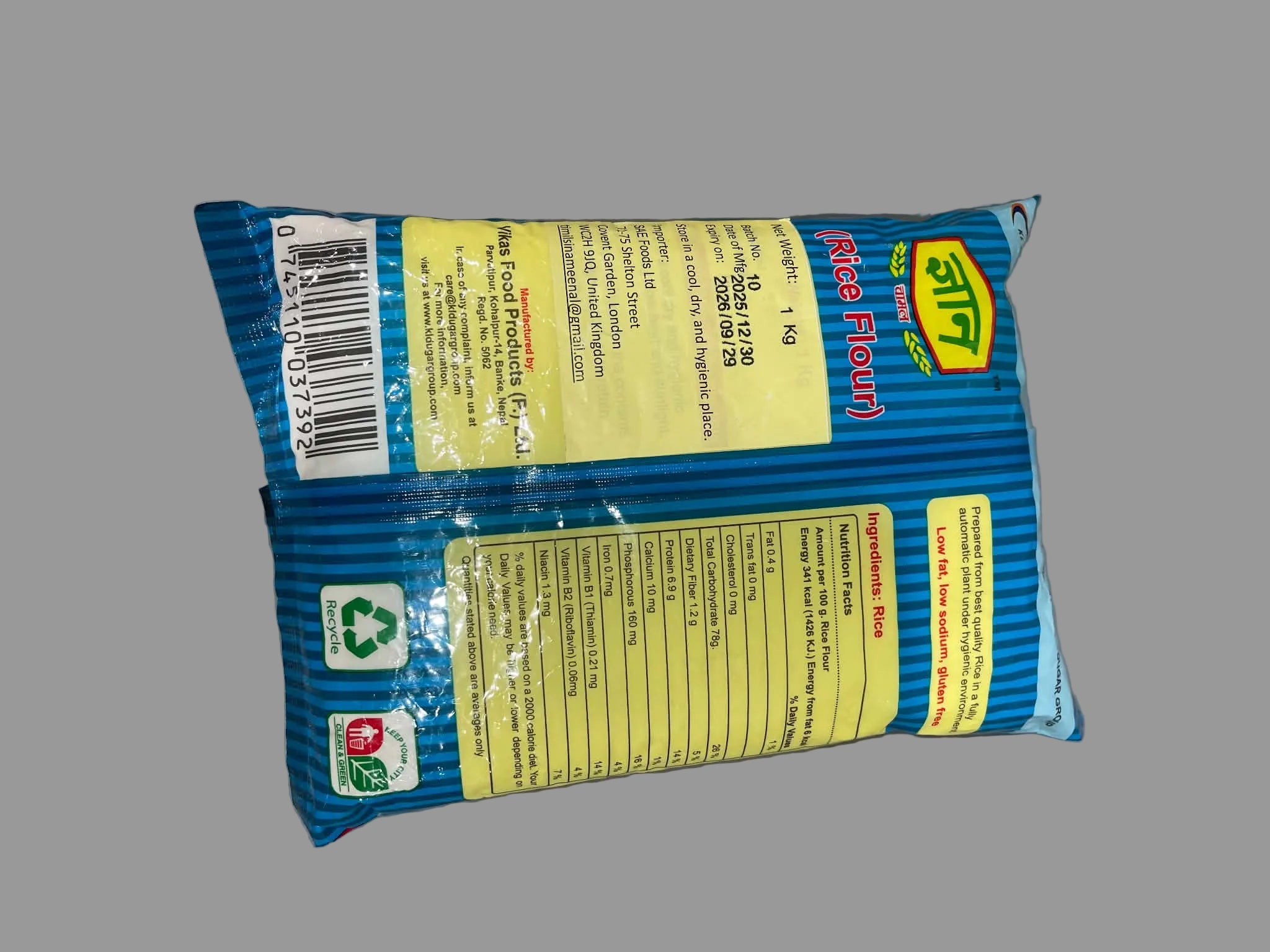 Back view of a blue and yellow bag of Saffron Flour (Wheat Flour) showing the barcode, ingredients, and recycling icons on a gray surface.