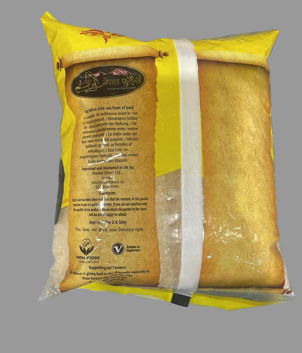 A package of Lalit Prakash Whole Wheat Bread, showing the back of the yellow and brown paper packaging with product details and a white plastic band sealing the bag.