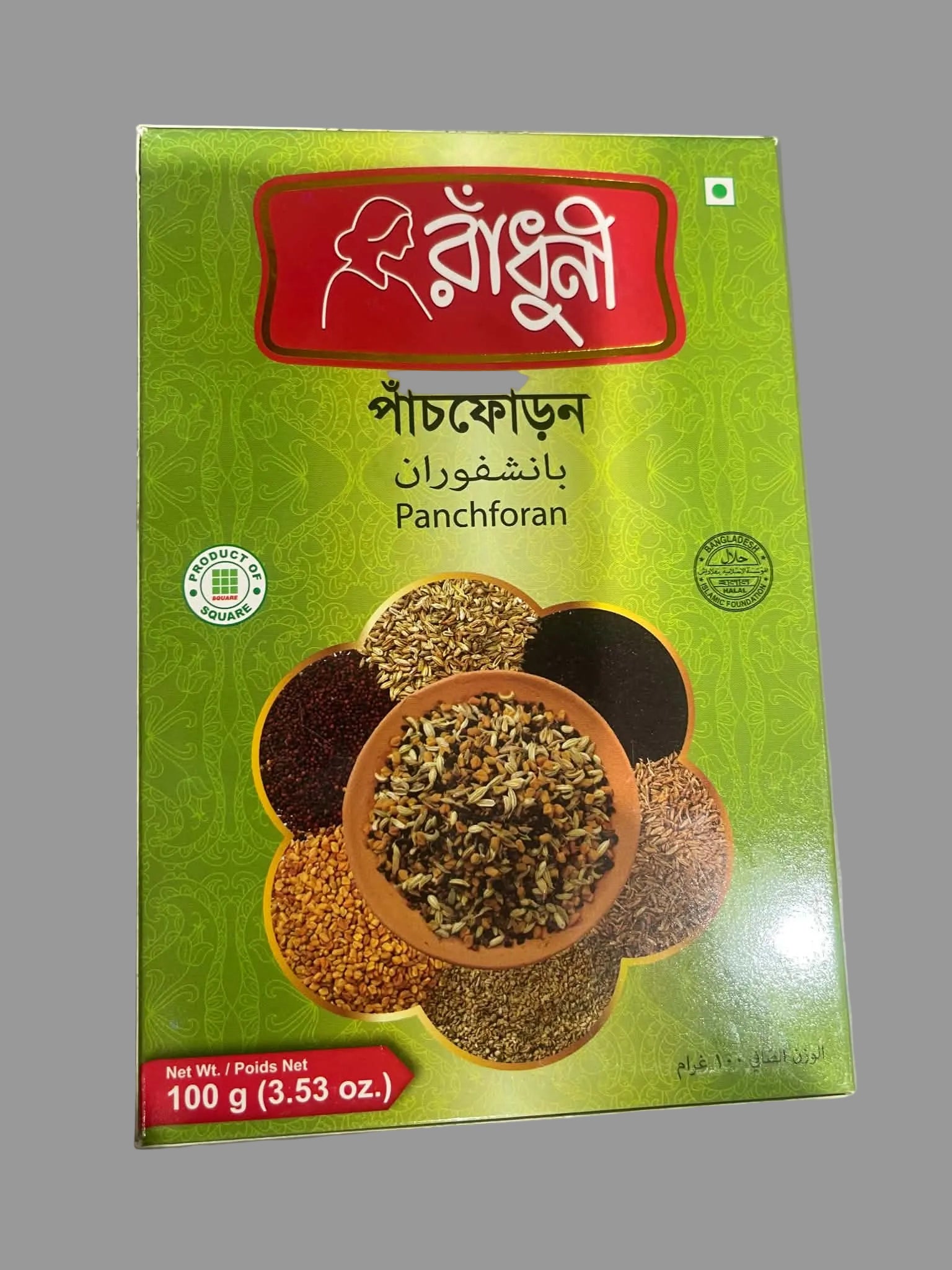 A 100g box of Bangladeshi Panchforan (five-spice blend) on a gray surface. The packaging is predominantly green with a red brand logo banner at the top and an illustration of various spices in bowls.
