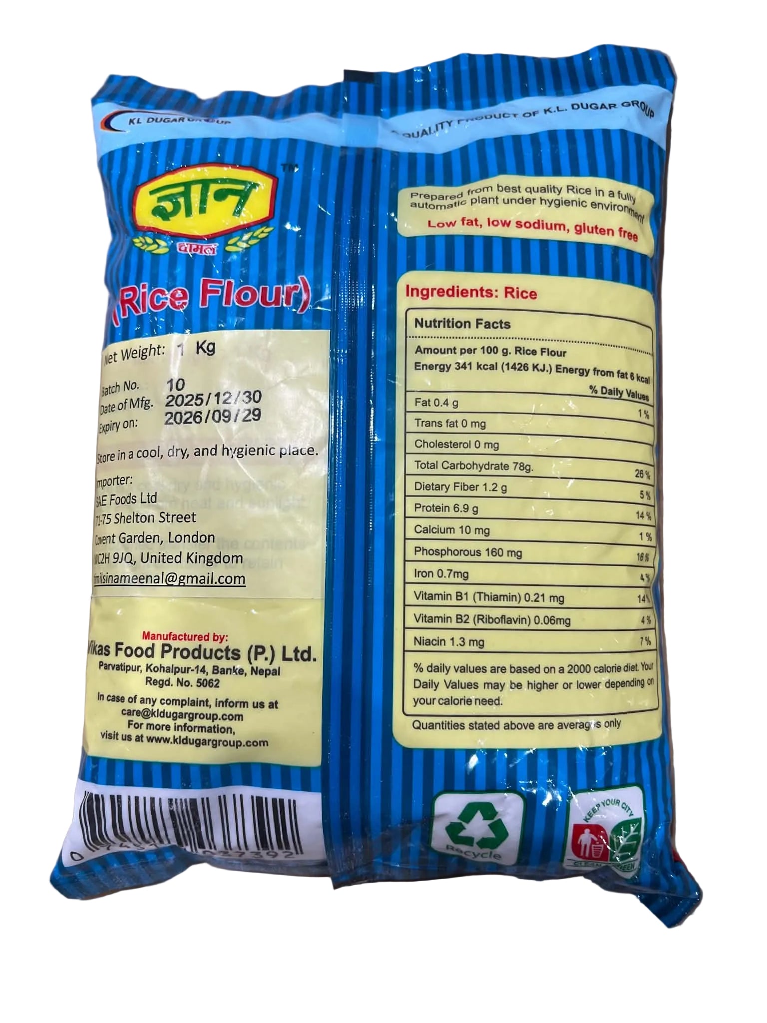 Back of a blue and yellow bag of Dhan Rice Flour, showing the ingredients list, nutrition facts, and barcode on a light brown surface.