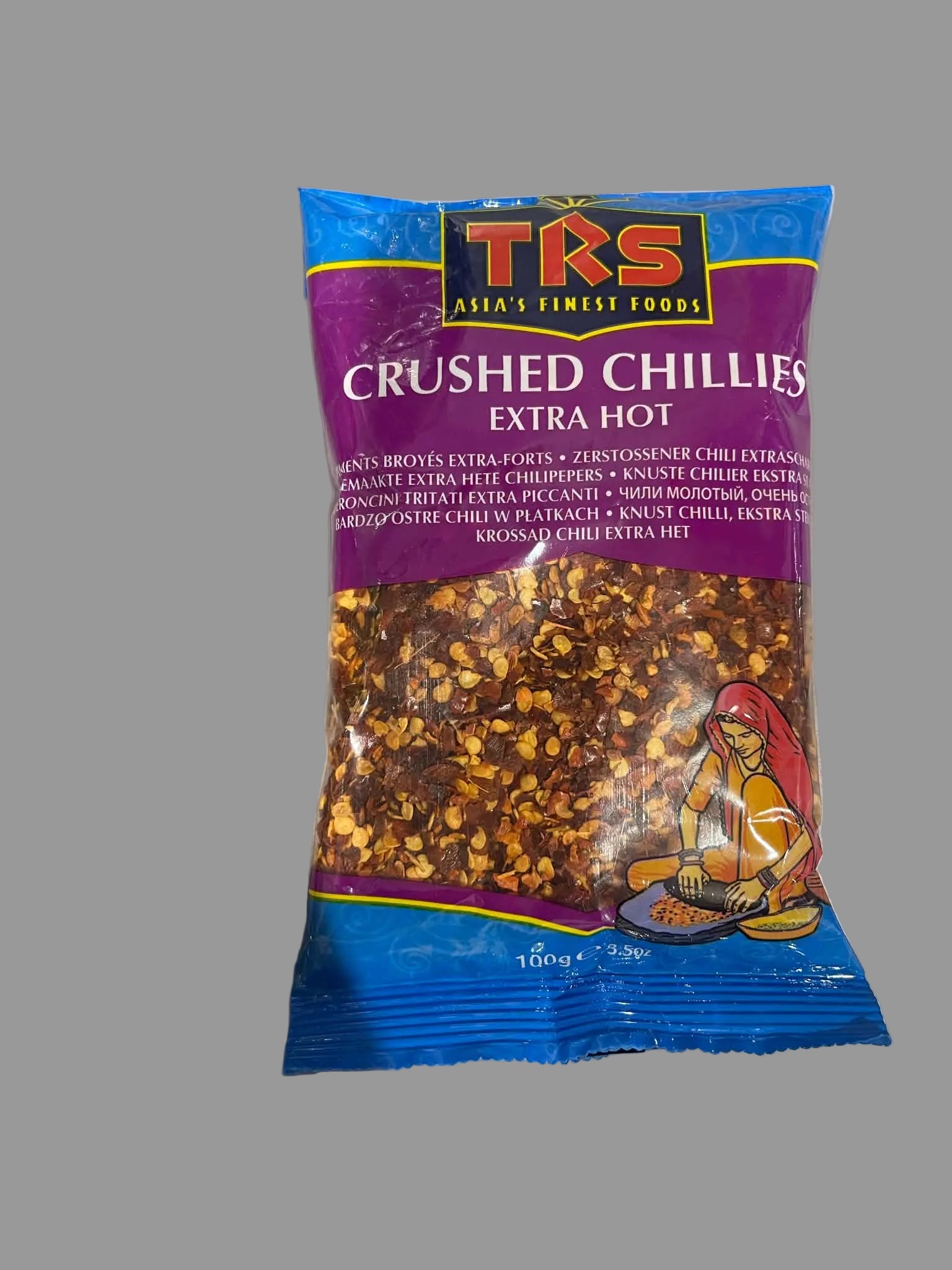 A 100g bag of TRS Crushed Chillies Extra Hot, featuring a purple and blue packaging design with a clear window showing the orange-red crushed chili flakes inside.