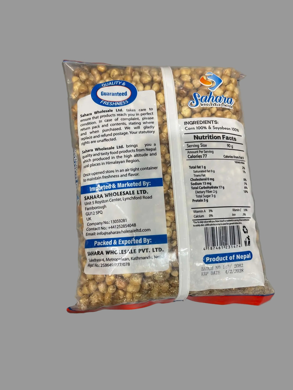 A clear plastic bag of Sahara Wholeseals roasted peanuts, showing the back side with product details, nutrition facts, and branding, held against a gray background.
