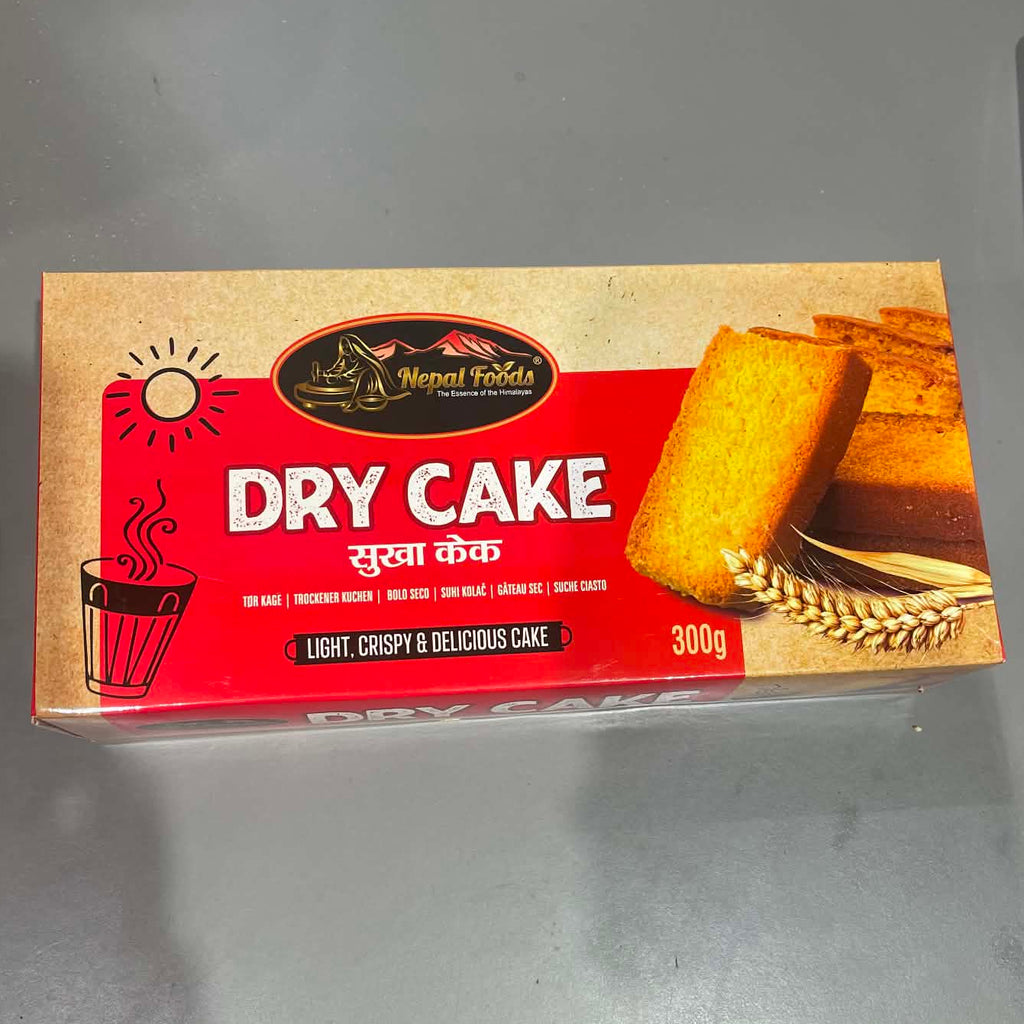A 300g box of Wheat Foods Dry Cake placed on a gray countertop, showing the product packaging with an image of a golden-brown cake slice.