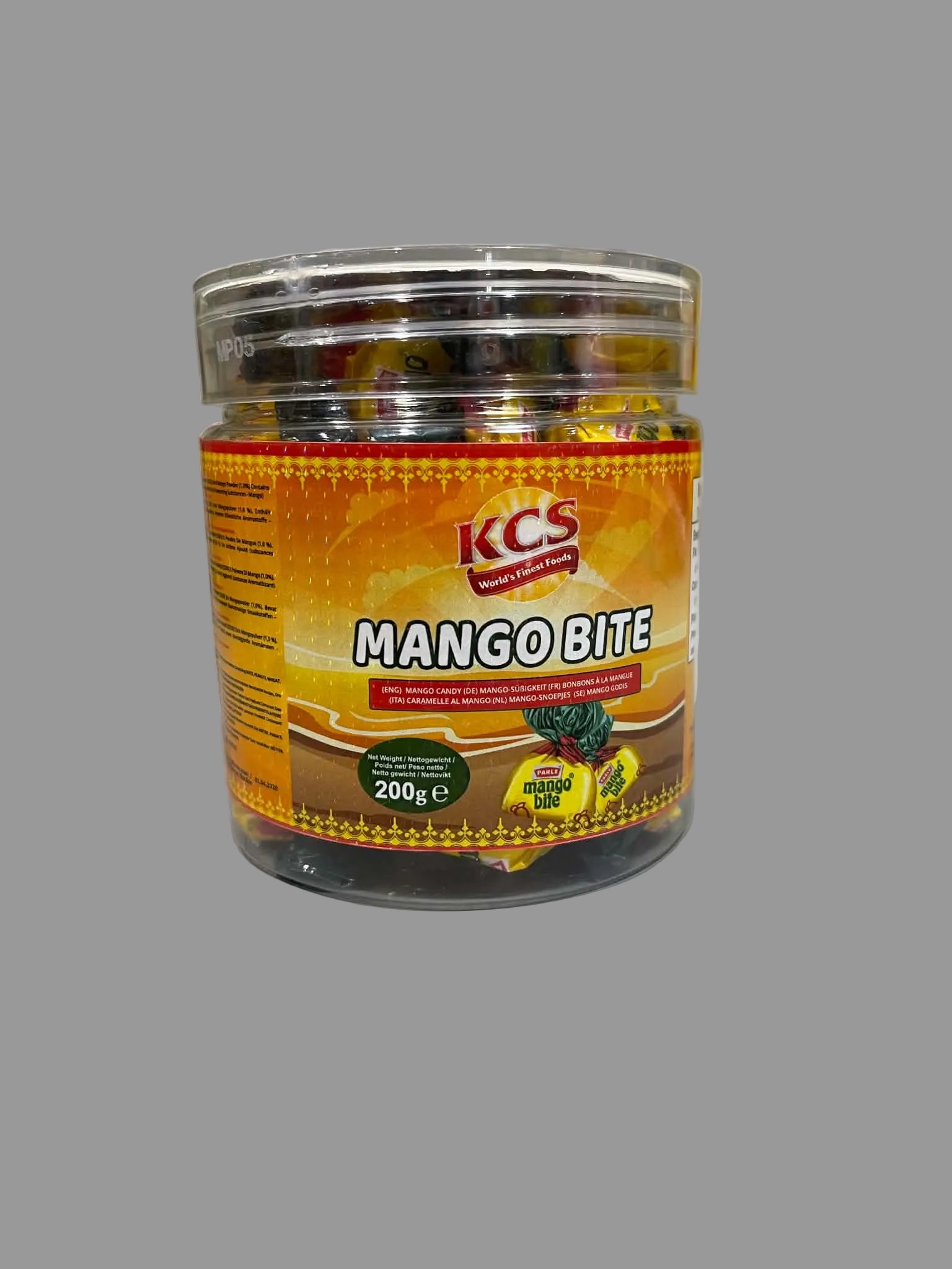 A clear plastic jar of KCS Mango Bite candies with a bright orange label, sitting on a light gray countertop.